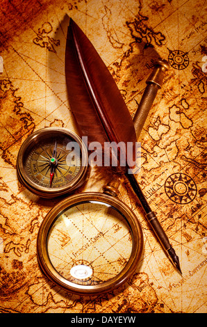 Vintage loupe, boussole, plume d'oie, spyglass allongé sur une vieille carte. Banque D'Images