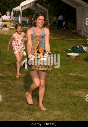 Femme transportant une partie de la demeure de son étal de voiture à la fin de la fête du Village Worldham, Hampshire, Royaume-Uni. Dimanche 14 juillet 2013. Banque D'Images