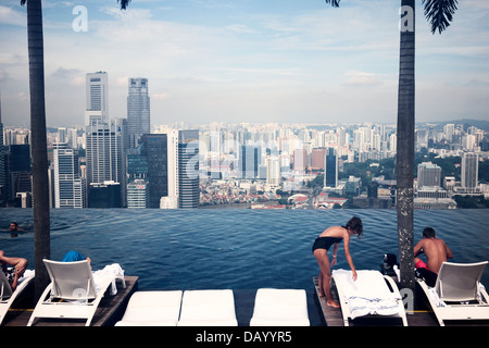 Les clients de l'hôtel bénéficiant d'horizon de la ville de Singapour par le Marina Bay Sand infinity pool deck Banque D'Images