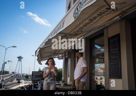 Une femme alléger sa cigarette en face d'un restaurant Banque D'Images