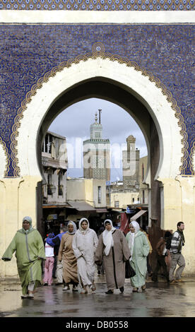 Les femmes avec des foulards de tête quitter la vieille ville (médina) à travers la porte Bab Boujeloud richement décorée en face de deux mosquées de l'arrière-plan, ville royale marocaine de Fès, Maroc, 29 mars 2007. Photo : Marijan Murat Banque D'Images