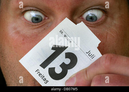 Un homme semble contre-eyed à une page de calendrier du vendredi 13 juillet à Schwerin, Allemagne, 12 juillet 2007. Beaucoup de gens superstitieux considèrent la date comme mauvais est de bon augure et certains même reporter des travaux importants ou de voyages si un jeudi coïncide avec le 13ème. Photo : Jens Buettner Banque D'Images