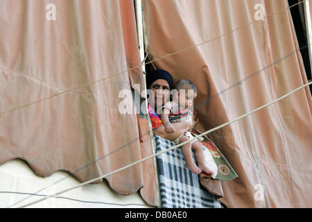 Une mère et son enfant par des pairs d'un écran solaire sur le pavé à la camp de réfugiés de Shatila à Beyrouth, Liban, le 19 juillet 2007. Photo : Rainer Jensen Banque D'Images