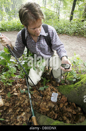 Un homme avec un appareil GPS recherche un refuge de chasse au trésor à Duesseldorf, Allemagne, 07 août 2007. Le GPS affiche des points de vue et les coordonnées pour vous aider à la recherche d'objets cachés (caches). Ce genre de paperchase a de plus en plus de fans. Environ 350.000 met en cache sont cachés dans le monde, environ 30.000 en Allemagne. Photo : Franz-Peter Tschauner Banque D'Images