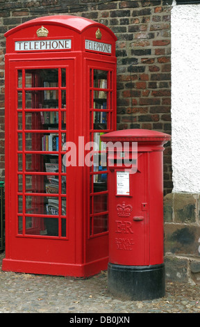 Un vieux téléphone britannique rouge fort transformé en un village britannique bibliothèque excentrique , à côté d'un poste de travail / pilier fort Banque D'Images