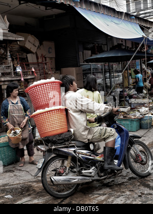 Livraison de motos en Thaïlande. Un garçon de livraison de glace avec une moto qui roule à travers un marché thaïlandais bondé. Thaïlande S. E. Asie Banque D'Images