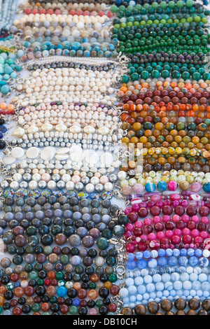 Les chaînes de perles colorées, bracelets et colliers sur une échoppe de marché en Italie, provenant de la province du Punjab, en Inde Banque D'Images