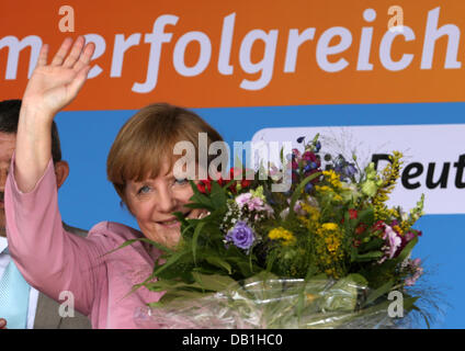 Zingst, Allemagne. 22 juillet, 2013. La chancelière allemande, Angela Merkel (CDU) vagues et est titulaire d'un bouquet de fleurs au début d'un événement de la campagne électorale en Zingst, Allemagne, 22 juillet 2013. Merkel se rendra dans trois villes dans sa circonscription en Mecklembourg-Poméranie-Occidentale le 22 juillet 2013. Photo : BERND WUESTNECK/dpa/Alamy Live News Banque D'Images
