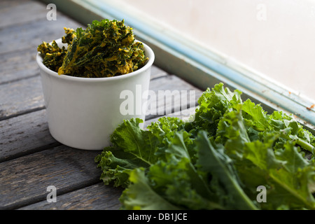 Bol de kale chips à côté de fresh kale Banque D'Images