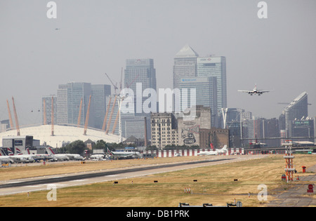 Un passager jet atterrit à l'aéroport de London City. Canary Wharf et le dôme du millénaire en arrière-plan Banque D'Images