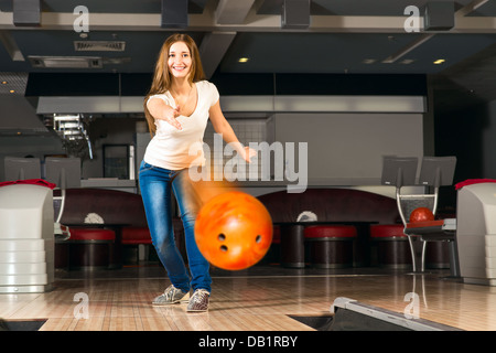 Agréable jeune femme jette une boule de bowling Banque D'Images