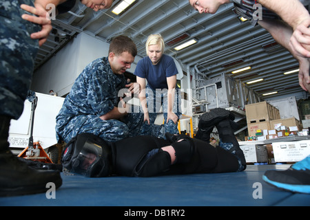 Ordnanceman Aviation aviateur Matthew Smith effectue un contrôle de l'avantage mécanique (MACH) sur Master-at-Arms 2e classe Nicholas Edick une fois pulvérisé avec l'aérosol capsique au cours de la formation de protection de la force à bord du navire d'assaut amphibie Banque D'Images