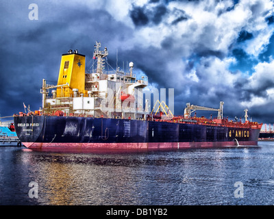 Cette scène montre un navire amarré dans une baie du port d’Amsterdam. L'eau calme reflète le navire et les éléments environnants, avec des nuages et le ciel ajoutant à l'atmosphère sereine du port. Le port est un élément clé du patrimoine maritime d'Amsterdam. Banque D'Images