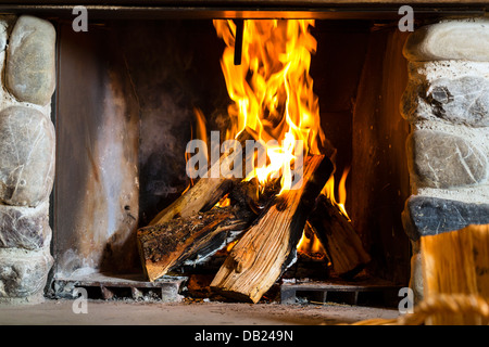 Incendie dans une cheminée rustique dans un refuge de montagne traditionnel Banque D'Images