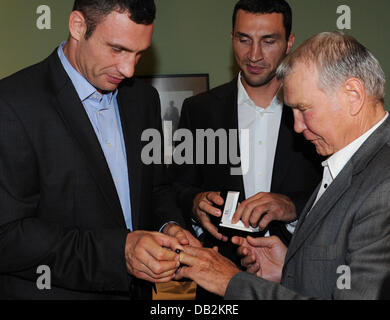 Boxeurs poids lourds Wladimir et Vitali Klitschko (l) présenter leur entraîneur Fritz Sdunek (m) avec un anneau à Hambourg, Allemagne, 15 septembre 2011. Les frères ont fait un anneau pour leur ami et aide à le remercier pour son soutien. Photo : Angelika Warmuth Banque D'Images