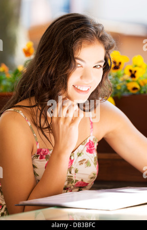 Jeune femme dans un restaurant menu lecture. Banque D'Images