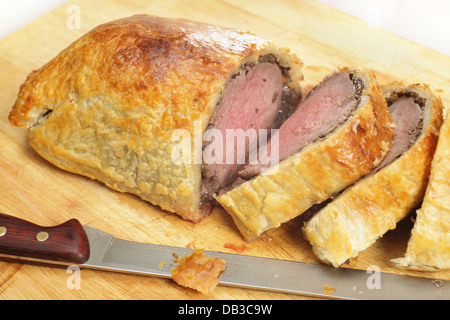 Un boeuf Wellington, ou de boeuf en croute, tranché sur une planche en bois, avec un couteau à découper Banque D'Images