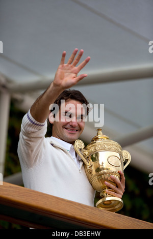 Roger Federer se tient sur le balcon des membres et présente le trophée à la foule à l'extérieur du Court central de Wimbledon Championships Banque D'Images