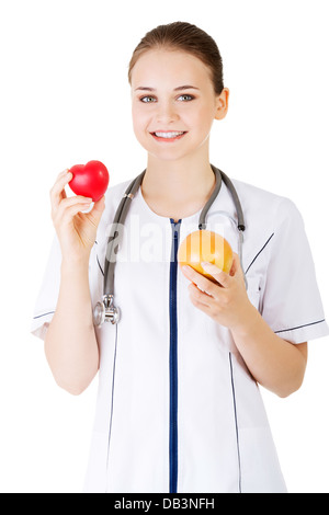 Female doctor holding pamplemousse sain et cœur rouge. Isolé sur blanc. Banque D'Images