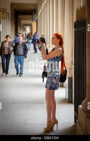 Grand modèle rousse en talons hauts en utilisant un DLSR, prendre des photos au Palais Royal, Paris France Banque D'Images