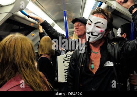 Un homme portant un masque anonyme voyages dans le métro, London, UK Banque D'Images
