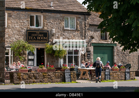 Les gens prendre des rafraîchissements, assis, manger & boire en plein air au soleil - à l'extérieur de la maison de thé, Kettlewell, North Yorkshire, Angleterre, Royaume-Uni. Banque D'Images