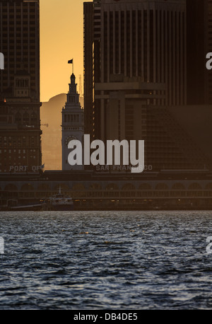 Le coucher de soleil de la ville illumine la tour et les silhouettes entourant les bâtiments du front de mer de San Francisco Banque D'Images Le coucher de soleil de la ville illumine la tour et les silhouettes entourant les bâtiments du front de mer de San Francisco Banque D'Images