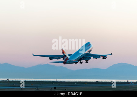 Un British Airways (BA) Boeing 747-400 (747-436) wide body jumbo jet airliner prend son envol au crépuscule, International de Vancouver YVR Banque D'Images