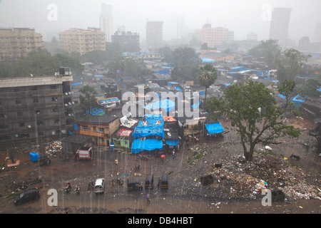 Une vue sur un bidonville avec des tours d'immeubles résidentiels dans l'arrière-plan lors d'une des pluies de mousson à Mumbai Banque D'Images