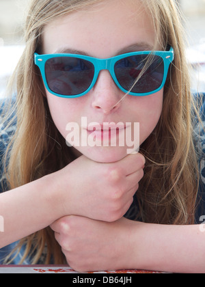 Teenage girl portrait avec les mains en appui sur les poings et portant des lunettes de soleil bleu. Son nom est Lara. Banque D'Images