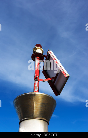 Petit phare avec ampoule rouge et panneau solaire Banque D'Images