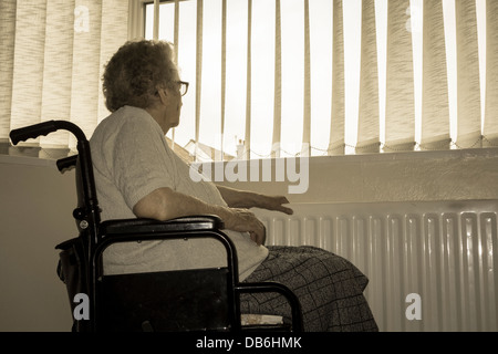 Femme de quatre-vingt-dix ans avec radiateur à la main regardant hors de la fenêtre. ROYAUME-UNI. Coronavirus, auto-isolement, distanciation sociale, quarantaine... concept Banque D'Images