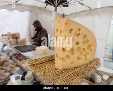 Big Cheese avec des trous. Un gros morceau d'Emmental-style, l'Emmental ou suisse est assis dehors sur un compteur du fournisseur de fromage. Banque D'Images