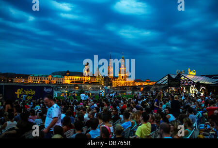 Dresde, Allemagne. 24 juillet, 2013. Les gens s'asseoir dans le cinéma en plein air en face du centre-ville historique de Dresde, Allemagne, le 24 juillet 2013. Sur les rives de l'Elbe, l'Église Hofkirche ( l'Église catholique de la Cour Royale de Saxe), le palais de la tour, le Georgentor et la Ständehaus (R-L) sont iluminated. Photo : Hannibal/dpa/Alamy Live News Banque D'Images