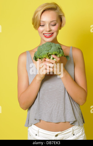 White Caucasian woman holding une couronne de brocoli et en souriant il Banque D'Images