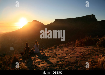 La femme meditatiing au lever du soleil sur le dessus de la tête des Lions avec la Montagne de la table en arrière-plan, Le Cap, Afrique du Sud Banque D'Images