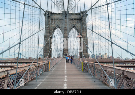 Les piétons marchant sur le pont de Brooklyn par une chaude journée d'été à New York. Banque D'Images