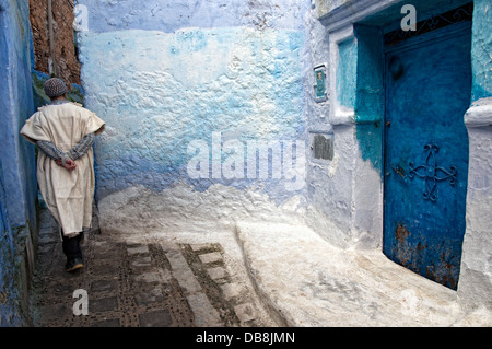 Homme marchant par les rues peintes en bleu clair de la médina. Région du Rif, Chefchaouen, Maroc Banque D'Images
