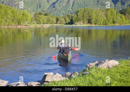 Haukeland Norvège Europe Deux jeunes hommes à loué à partir de la pagaie de canoë sur le lac calme Haukeland banque Banque D'Images