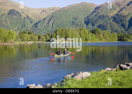 Haukeland Norvège Europe Deux jeunes hommes une pagaie canoë loué à travers lac calme Haukeland Banque D'Images