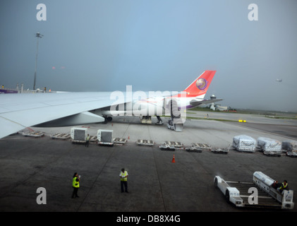 Sur le tarmac de l'avion à l'aéroport avec l'aile d'avion en Thaïlande et deux couche de sécurité avec du personnel et transport service baggage cart Banque D'Images