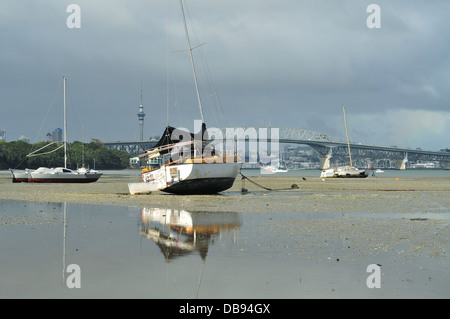 Voiliers reposant sur fond vaseux à marée basse avec Auckland Harbour Bridge et la Sky Tower, à distance Banque D'Images