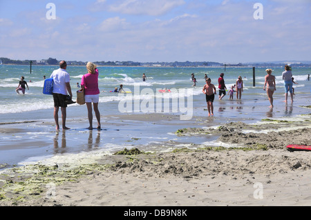 Couple avec des nageurs aux beaux West Wittering plage pavillon bleu, nr. Chichester, West Sussex, UK à Hayling Island in distance Banque D'Images