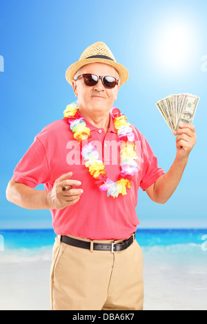 Satisfait monsieur holding un cigare et de dollars, sur une plage Banque D'Images