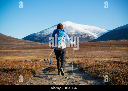 Female hiker randonnées nord sur la piste couverte de neige avec Kungsleden Keron/Giron (1543m) pic de montagne à distance, Laponie, Suède Banque D'Images