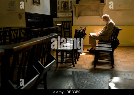 Un homme qui prie à St Pancras Old Church, Somers Town, Londres. Banque D'Images