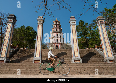 Une femme non identifiée rides son vélo en face de la pagode de Thien Mu, 12 janvier 2008 à Hue, Vietnam. Banque D'Images