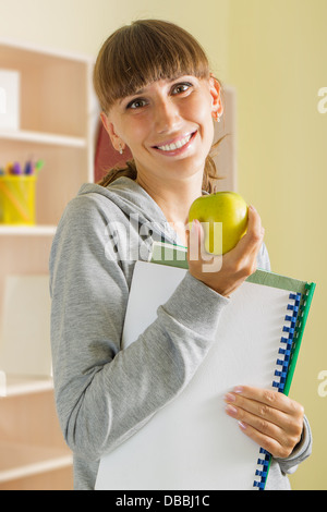 Young smiling girl avec apple et cahiers scolaires Banque D'Images