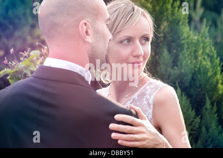 Bride and Groom posant dans le jardin sous le soleil d'après-midi Banque D'Images