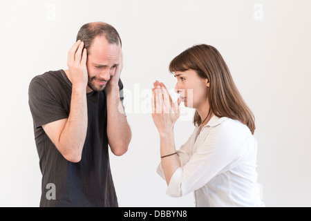 Jeune adulte homme femme tout en couvrant ses oreilles lui crie Banque D'Images